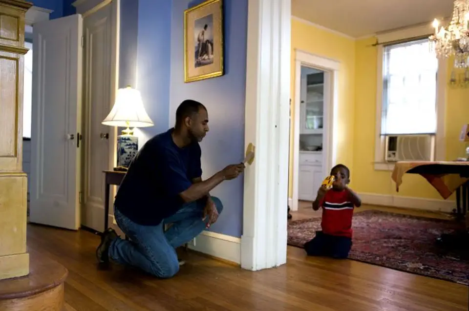 Home project DIY: Interior. Photo of man fixing door jamb with child playing in other room.
