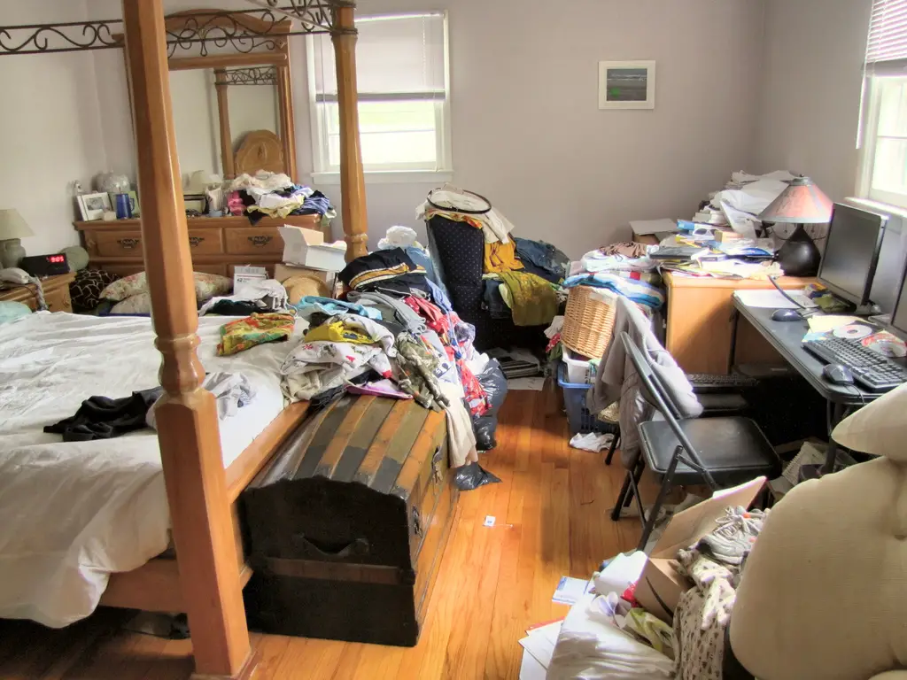 a bedroom completely covered by clothes and laundry