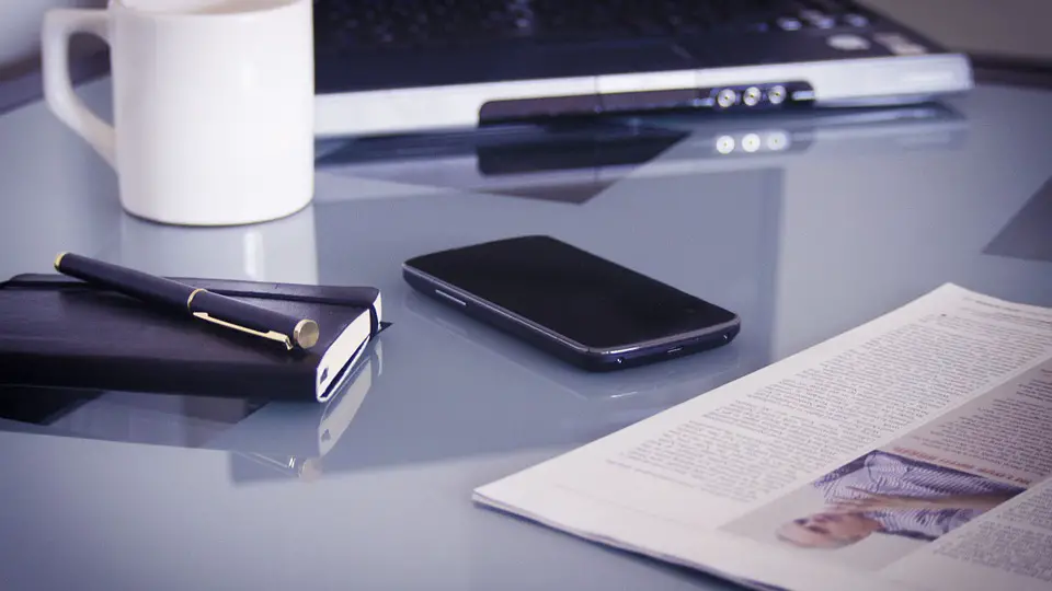 a desk with coffee, a packet of papers, and a laptop