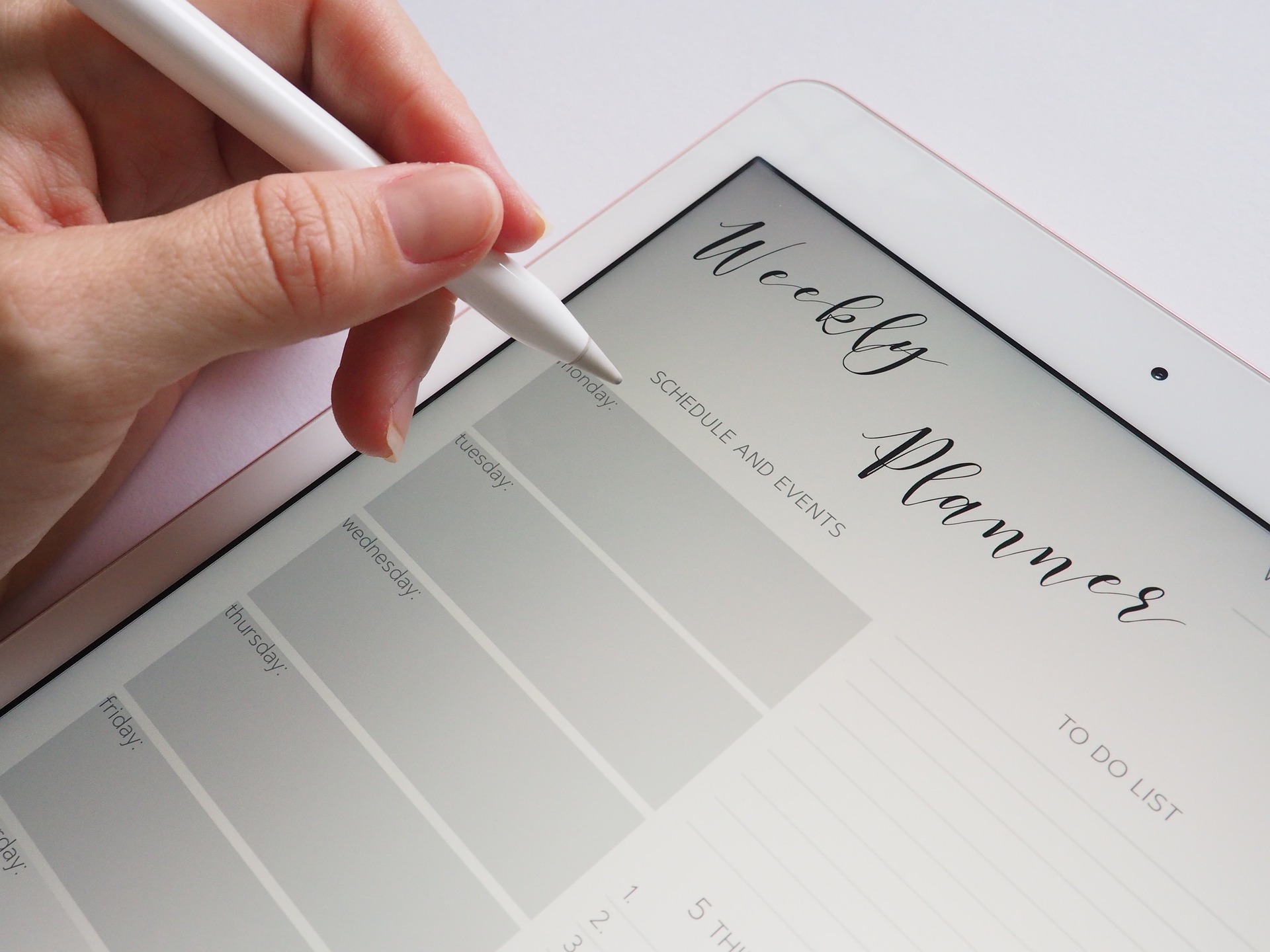 image of a woman holding an apple pencil with a weekly planner on her iPad