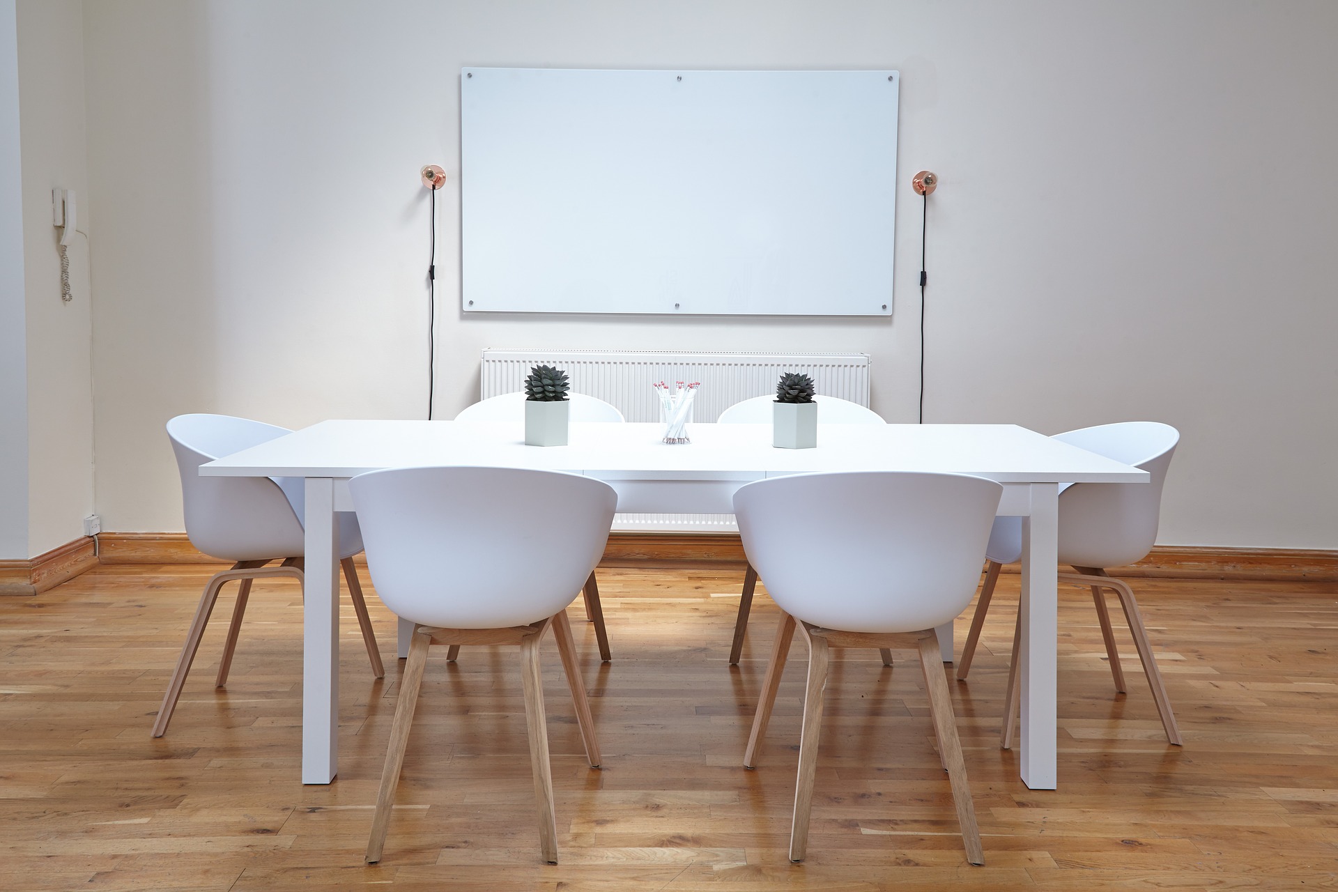 a simple dining room with white bucket chairs and a blank paint canvas hung on the wall