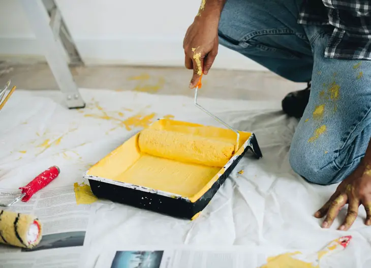 man holding yellow paint roller