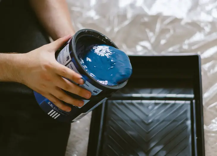 person holding can of blue paint