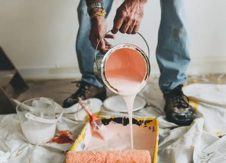 person holding pink paint bucket pouring